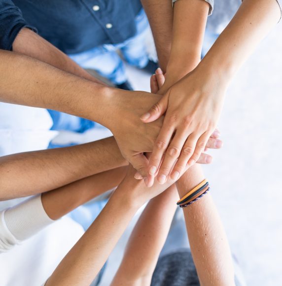 Close up top view of young business people putting their hands together. Stack of hands. Unity and teamwork concept.